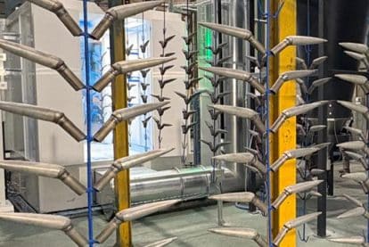 Componenti metallici conici durante il processo di verniciatura a polvere su impianto industriale automatico